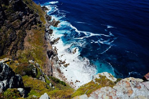 Free A breathtaking view from a cliff overlooking the vibrant turquoise ocean waves crashing against the rocky shore. Stock Photo