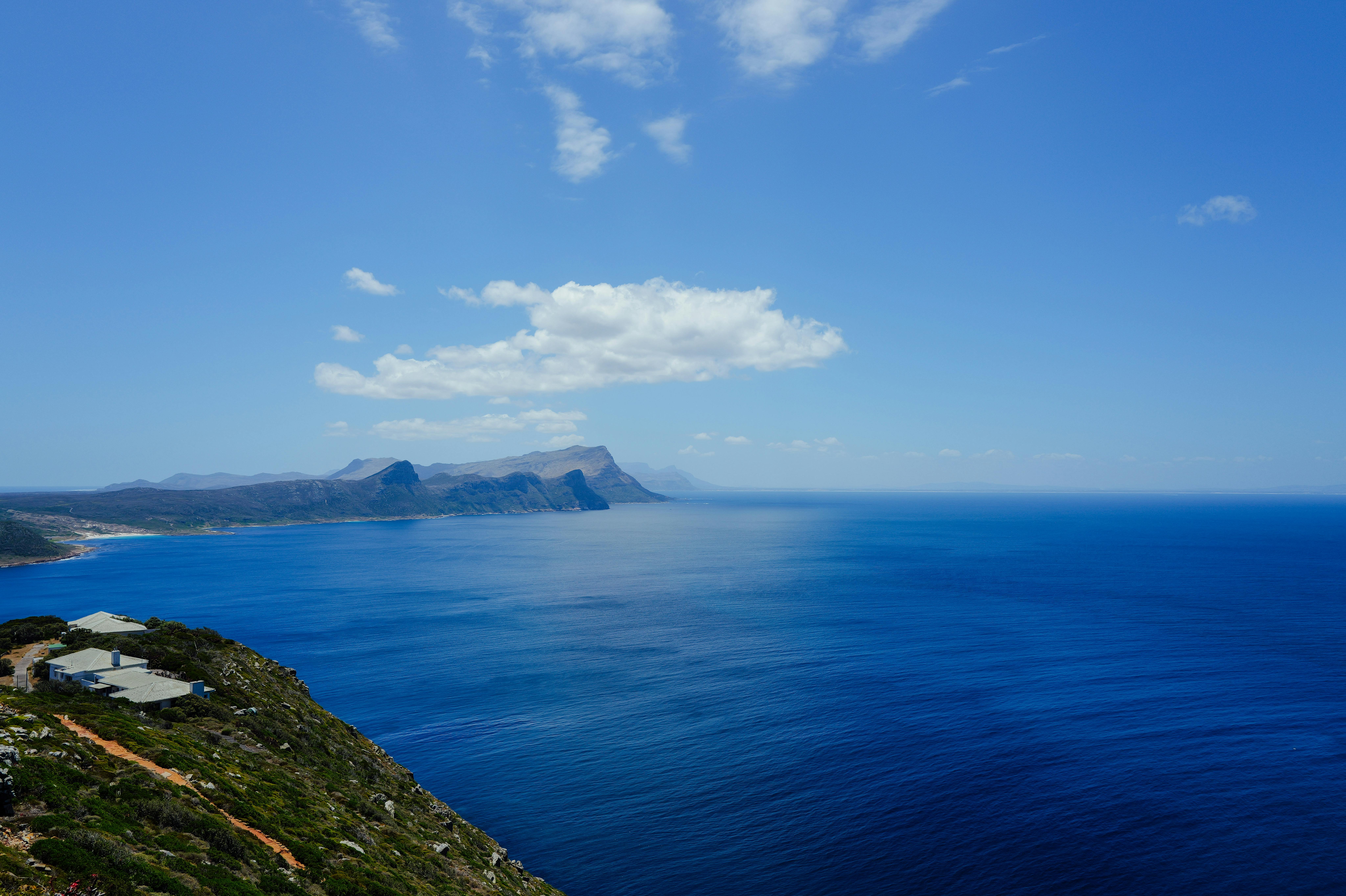 무료 구름으로 가득 찬 밝은 하늘 아래 험준한 해안선과 맑고 푸른 바다가 어우러진 숨막히도록 아름다운 풍경. 스톡 사진