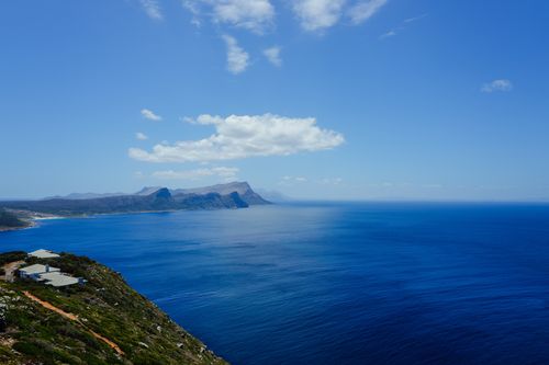Free Breathtaking view of a rugged coastline and clear blue ocean under a bright sky filled with clouds. Stock Photo
