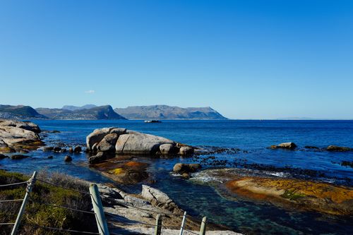 Free Beautiful view of a clear blue sea with rocky coastline and mountains in the background. Stock Photo