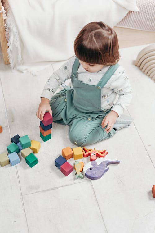 Free A Child Sitting on The Floor Playing With Toys Stock Photo