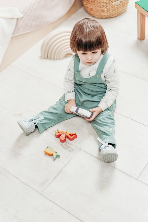 Ребенок сидит на полу с игрушками