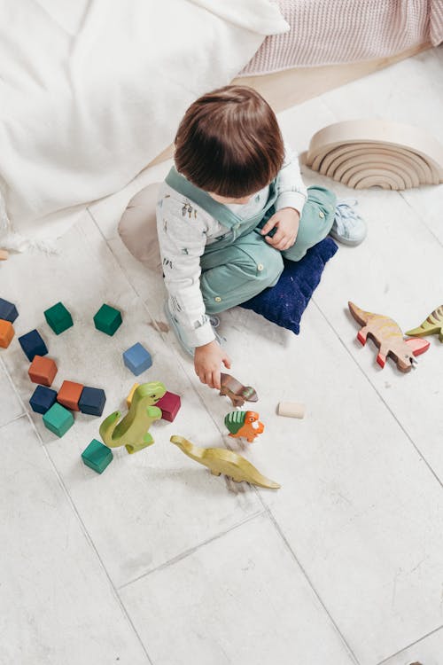 Bambino In Maglia Bianca A Maniche Lunghe E Pantaloni Salopette Che Giocano Con Blocchi Di Lego Colorati