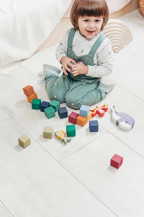 Enfant En Haut à Manches Longues Blanc Et Pantalon Salopette Bleu Sarcelle Jouant Avec Des Blocs Lego