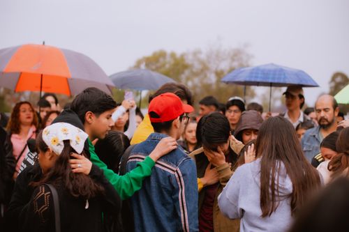 Free A group of diverse adults and teenagers gather under umbrellas on a cloudy day, showing support and empathy. Stock Photo