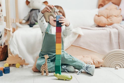 Enfant En Haut à Manches Longues Vert Et Blanc Et Pantalon Salopette Tenant Des Blocs Lego Bleu Et Jaune