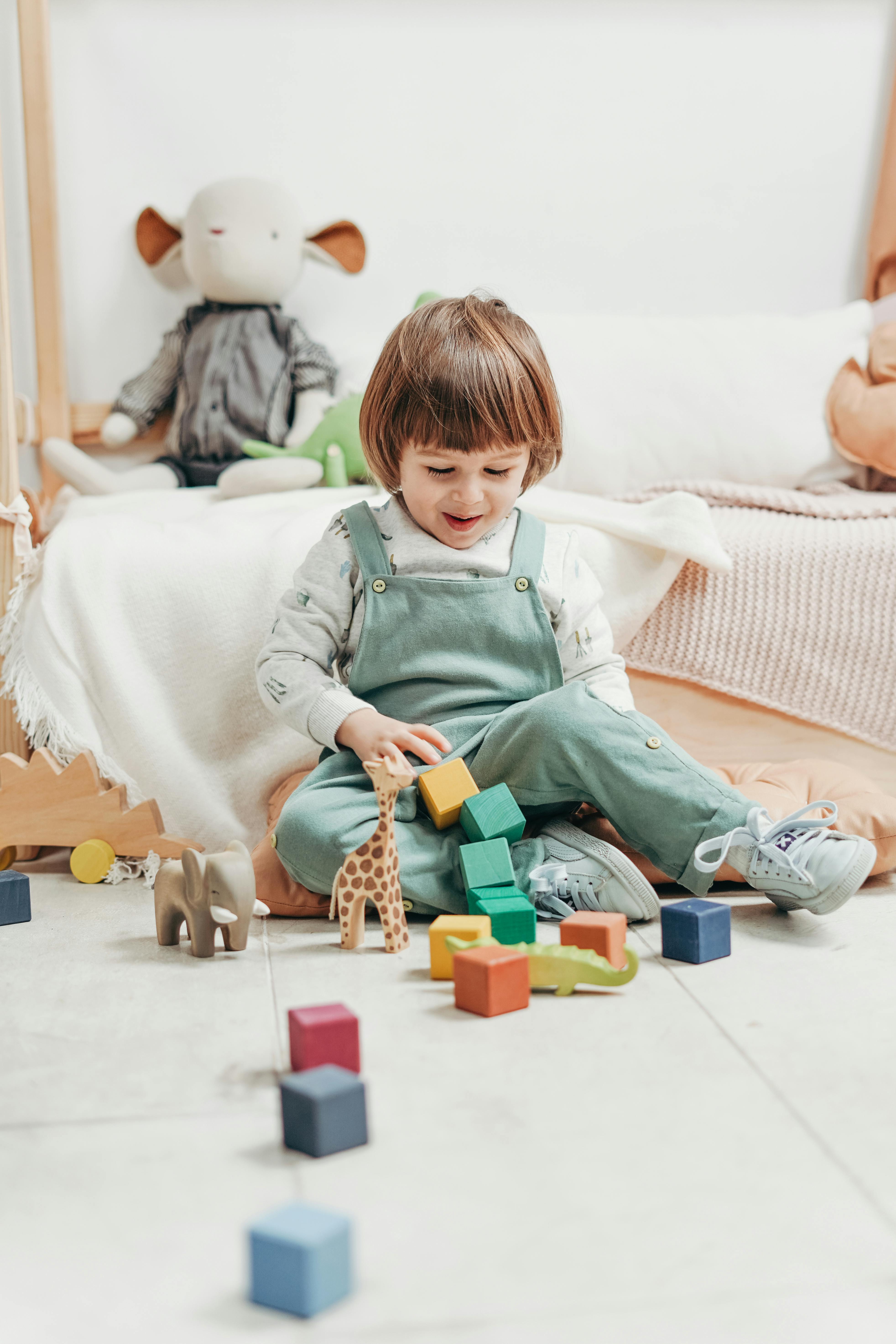 Child in White Long-sleeve Top and Dungaree Trousers Playing With Lego ...