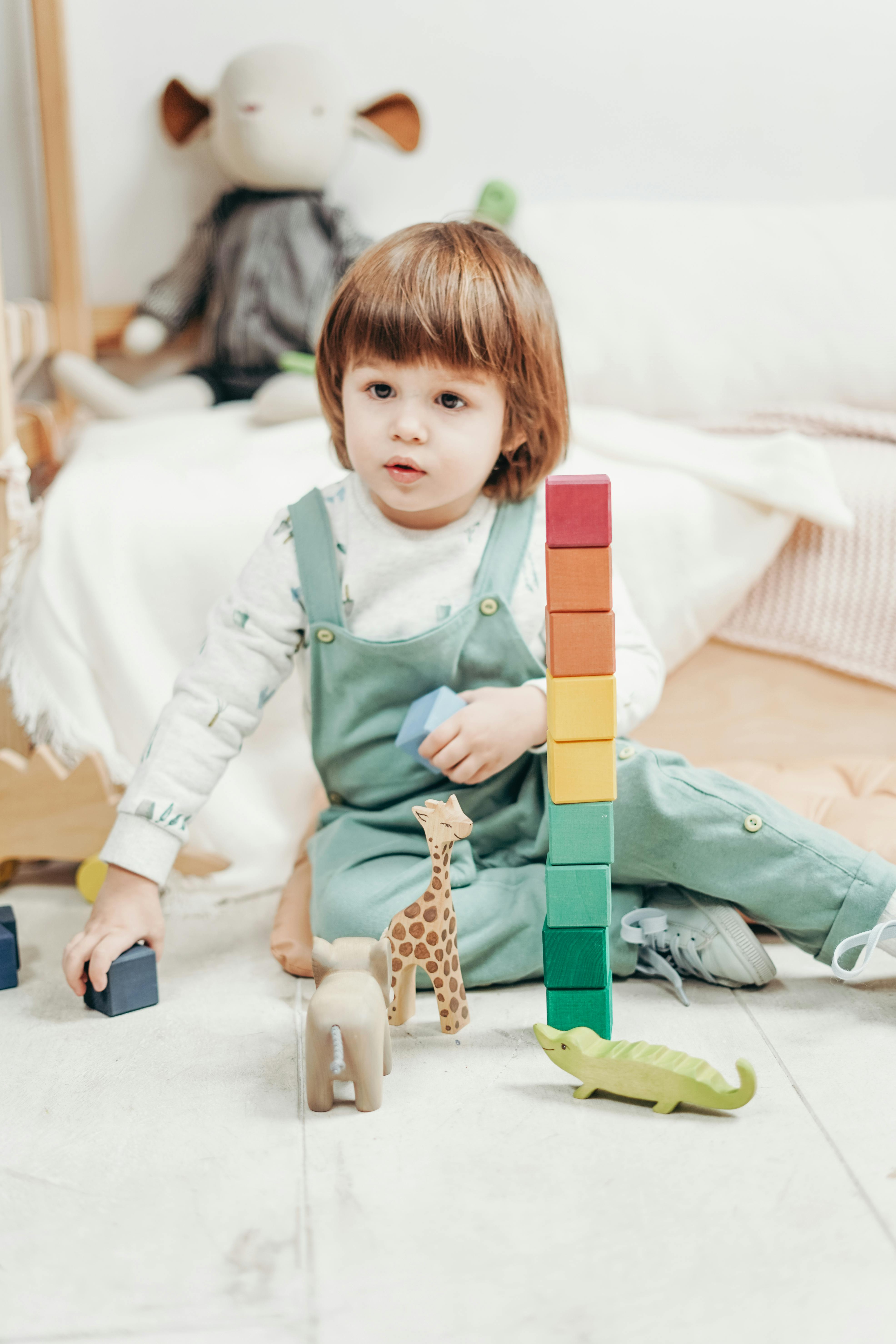 Child in White Long-sleeve Top and Dungaree Trousers Playing With Lego ...