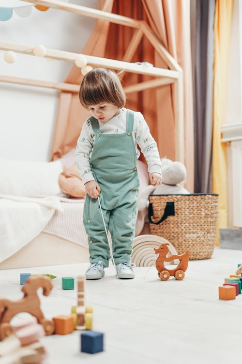 Ein Kind, Das Die Spielzeuge Auf Dem Boden Betrachtet