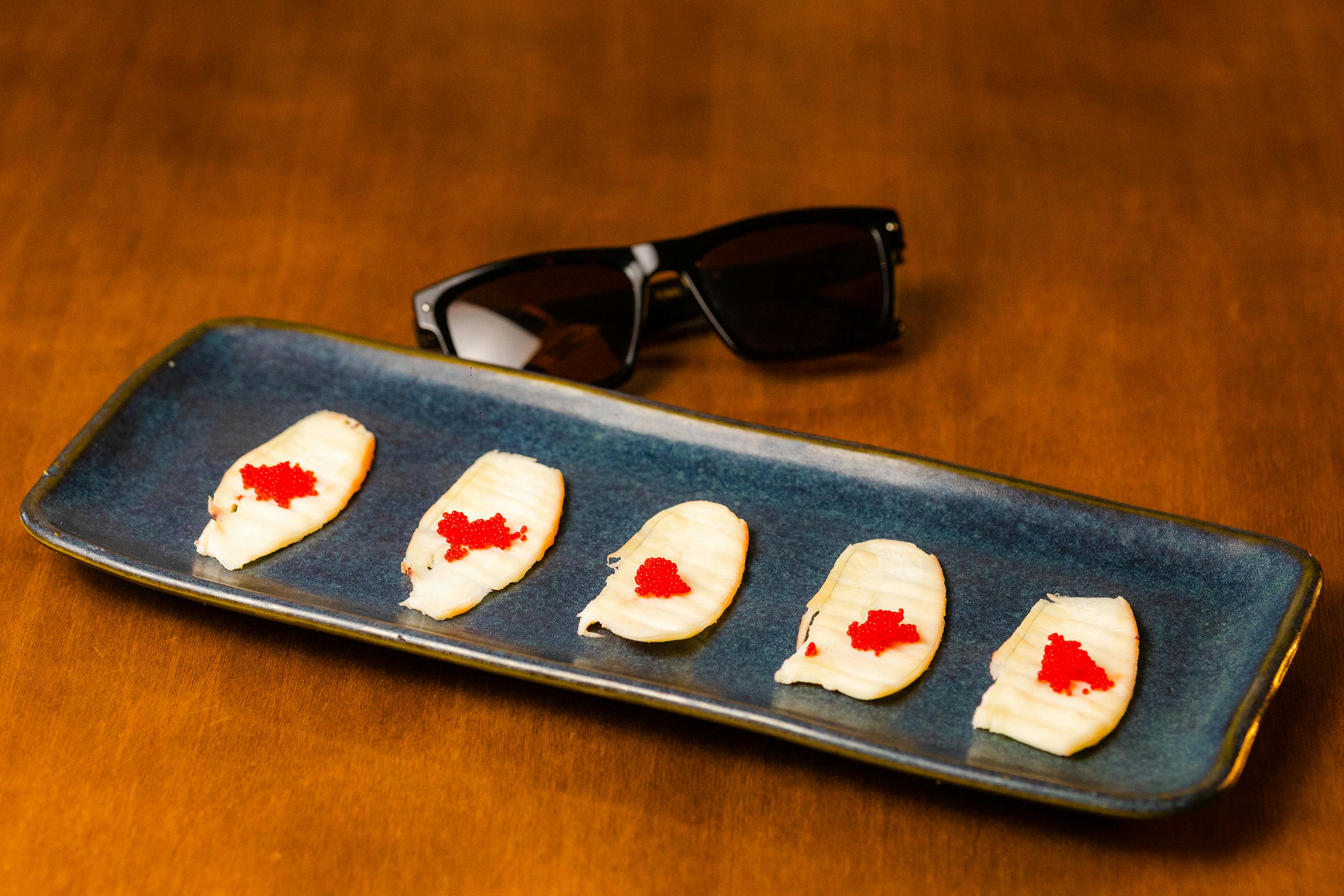 Zadarmo Štýlová prezentácia sushi s ikrami na modrom tanieri popri tmavých slnečných okuliaroch, elegantná kulinárska scéna. Fotka z fotobanky