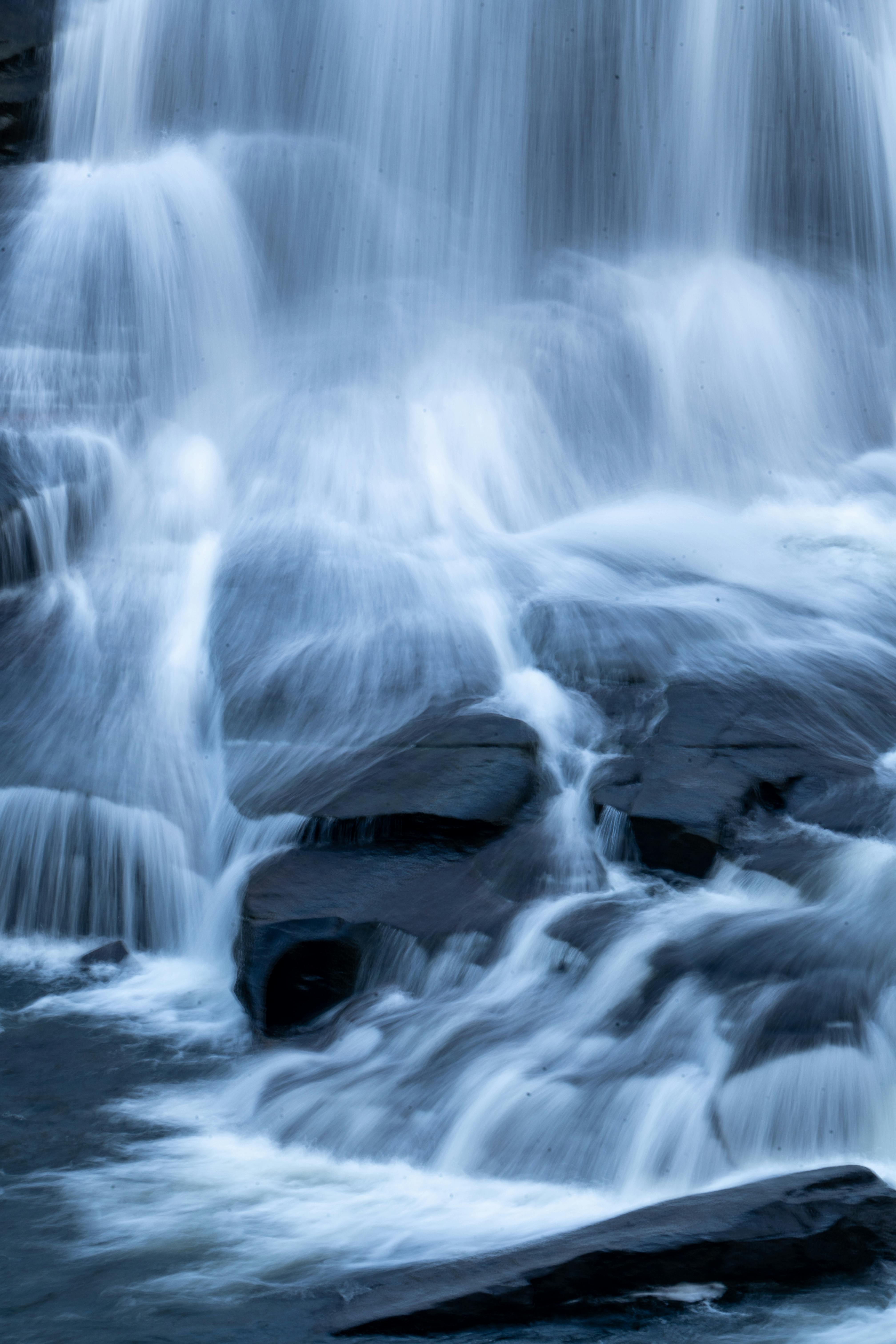Zadarmo Záber pokojného vodopádu stekajúceho cez hladké skaly v lesnom prostredí s dlhou expozíciou. Fotka z fotobanky