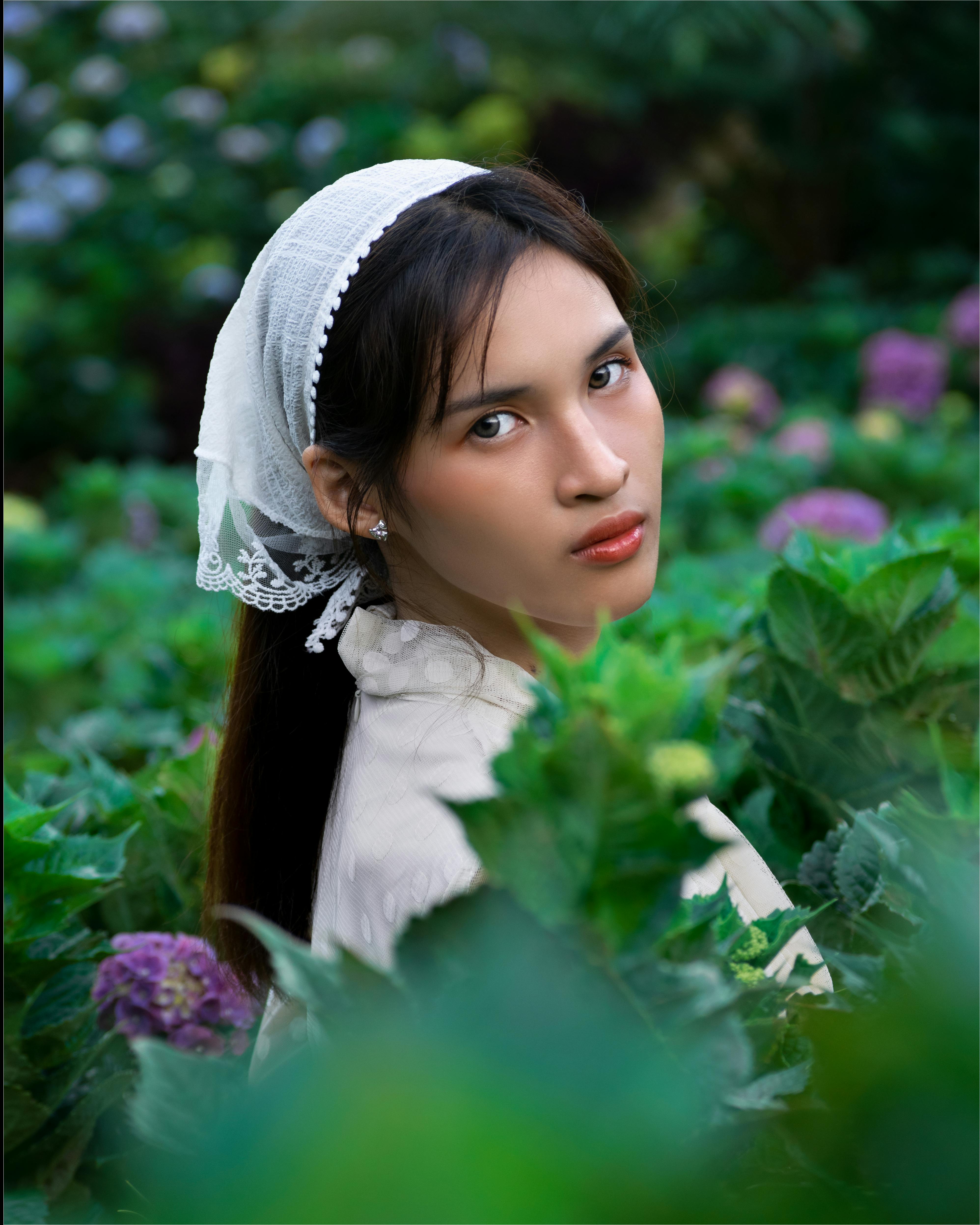 Zadarmo Elegantná žena s čipkovanou šatkou na hlave obklopená žiarivými hortenziami. Fotka z fotobanky