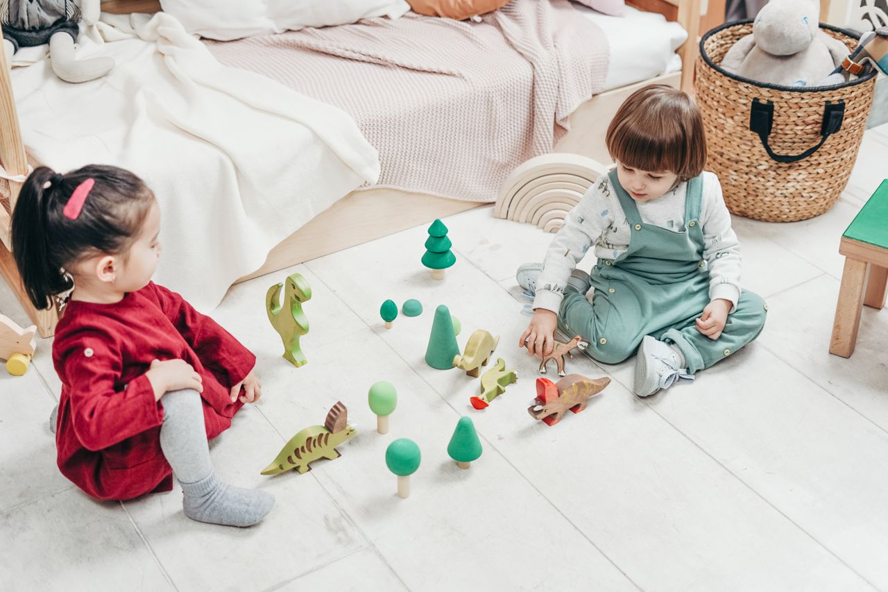 two kids enjoying playtime with wooden toys in a cozy bedroom setting