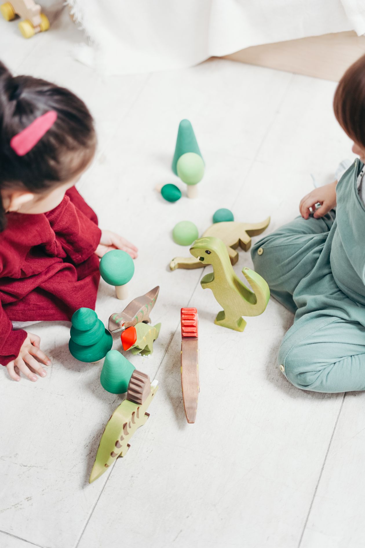 Two children playing with wooden toys on the floor