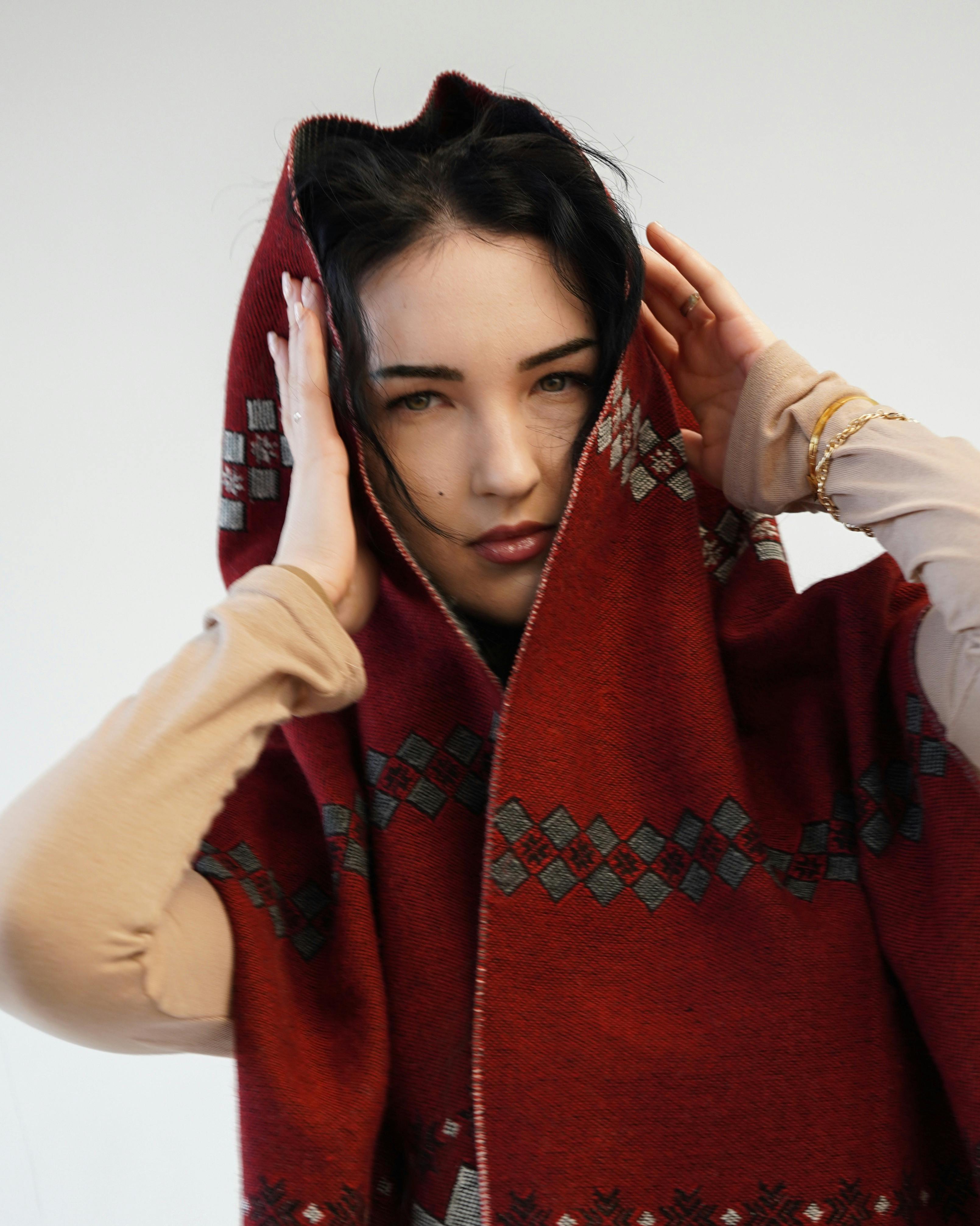 Zadarmo Módny portrét ženy v červenom vzorovanom šále s kapucňou na neutrálnom pozadí. Fotka z fotobanky