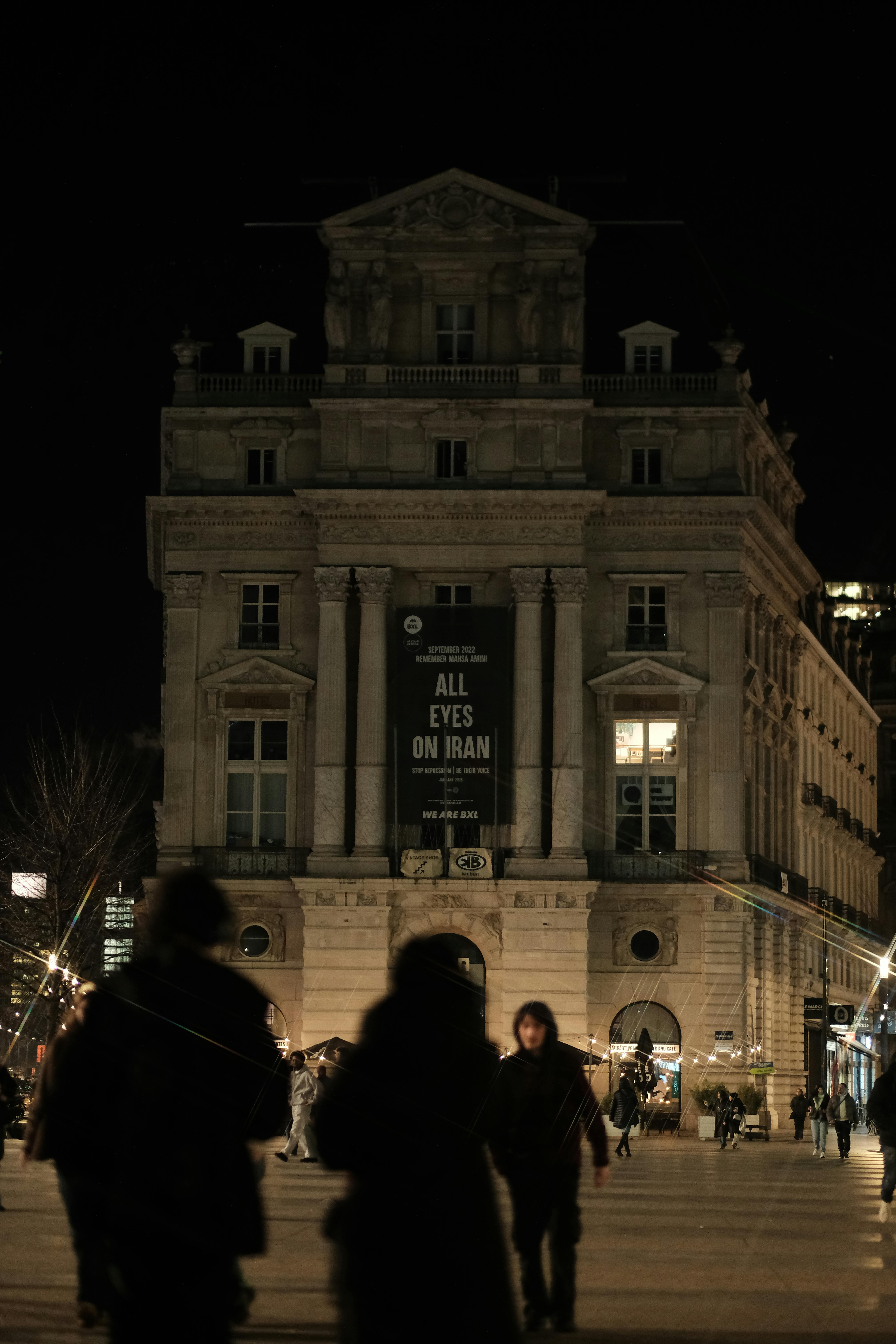Zadarmo Nočný pohľad na Brusel s ľuďmi kráčajúcimi v blízkosti historickej budovy. Fotka z fotobanky