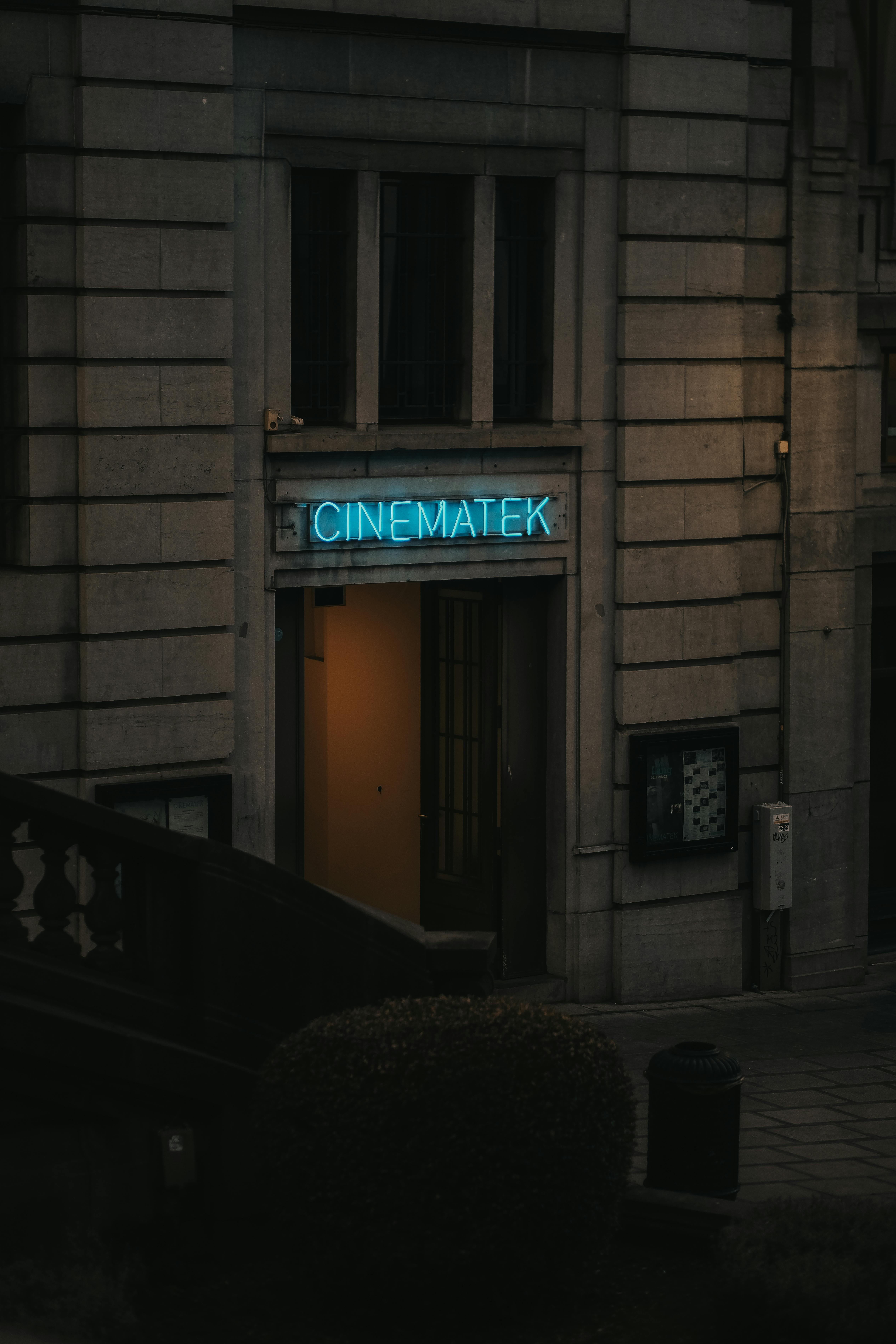 무료 브뤼셀 시네마테크 입구의 야경으로, 고전적인 건물 외관을 배경으로 빛나는 네온사인이 눈길을 사로잡습니다. 스톡 사진