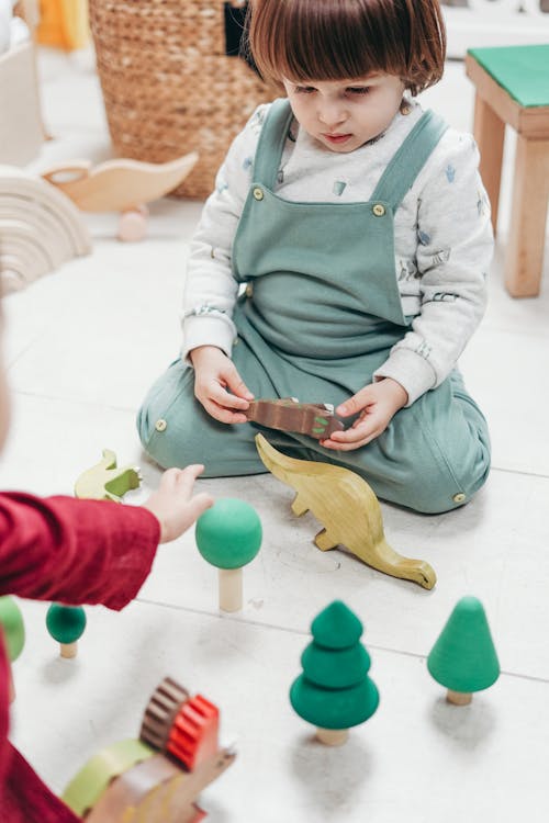 Free baby in Green Apron Holding Brown Wooden toy Stock Photo