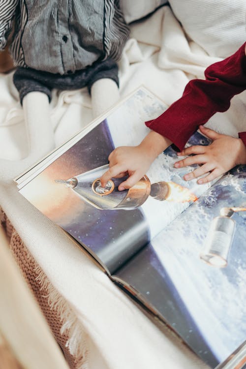 Free Child Hand Pointing to a Spaceship Illustrated on Book  Stock Photo