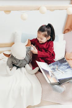 可爱的亚洲女孩坐在室内的床上，开心地玩着毛绒玩具