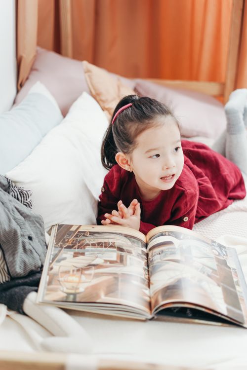 Free A young child enjoying a book in a comfortable, cozy bedroom environment. Stock Photo