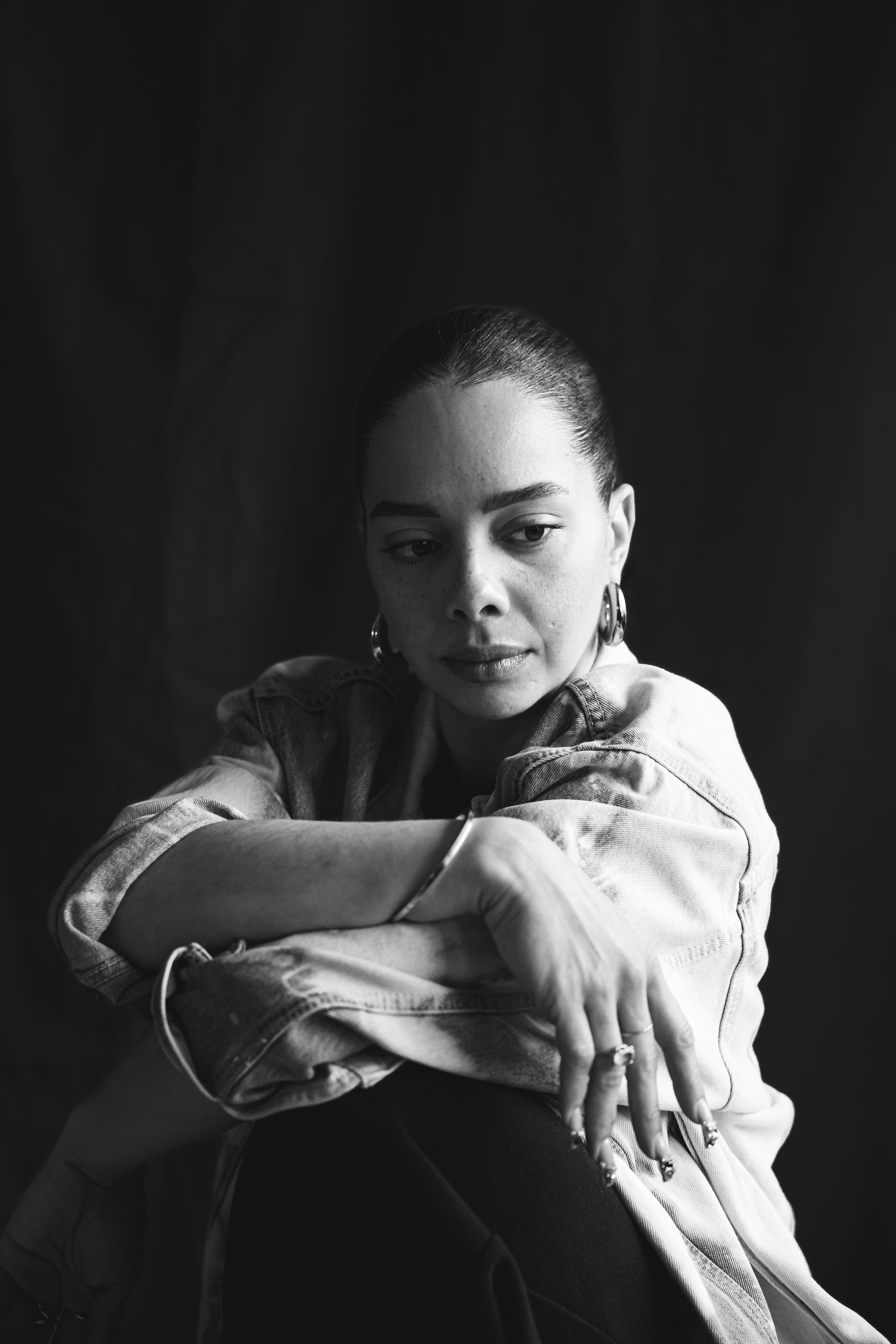 Moody black and white portrait of a woman lost in thought, wearing denim.