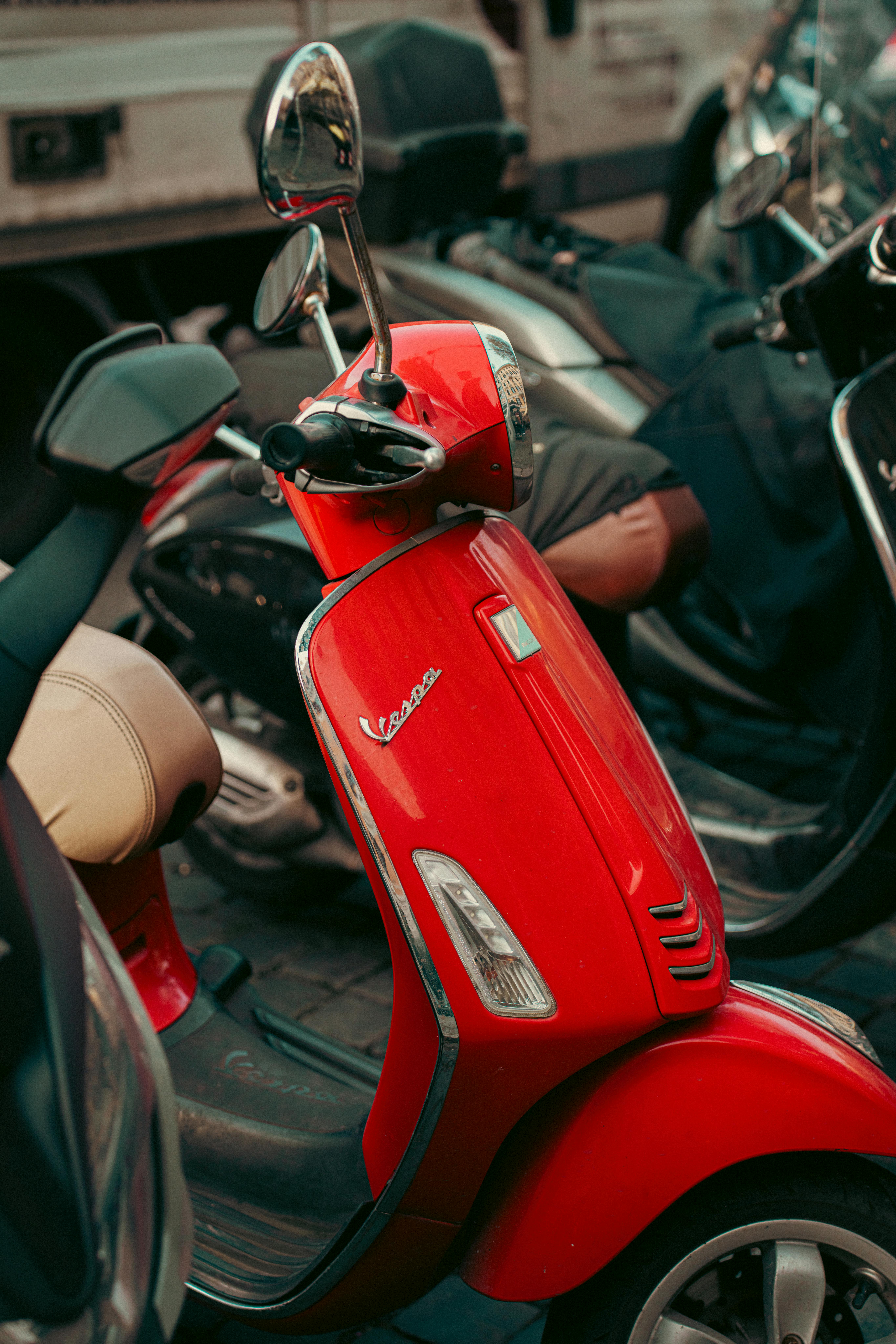 Безкоштовне Яскраво-червоний скутер Vespa припаркований серед інших транспортних засобів на вулиці в Римі, Італія. стокове фото