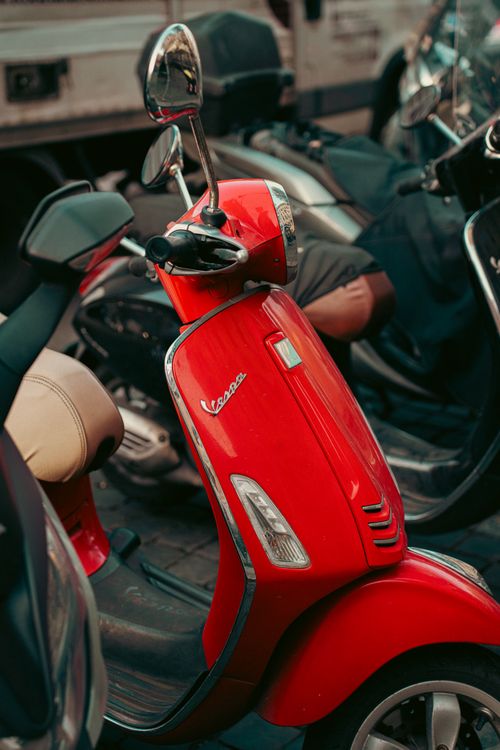 Free Bright red Vespa scooter parked among other vehicles on a street in Rome, Italy. Stock Photo