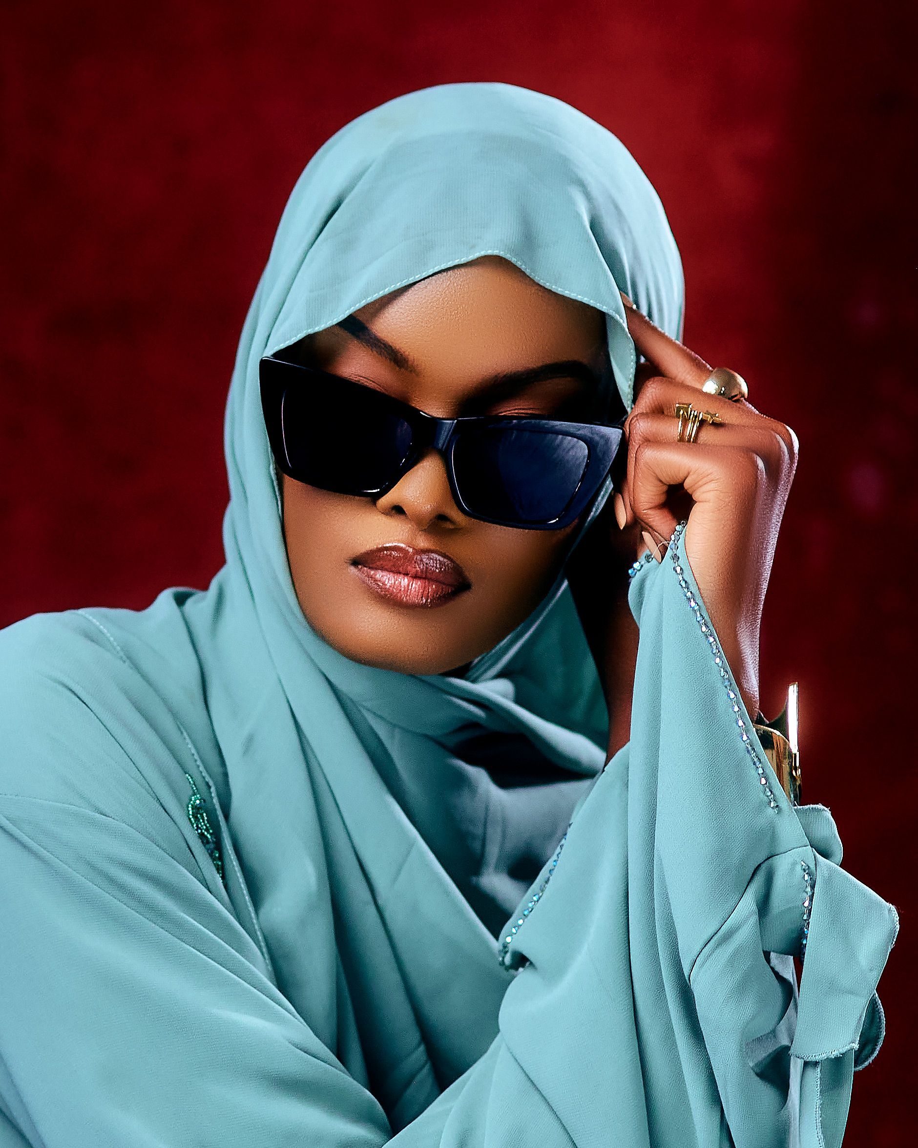 Elegant portrait of a woman in a turquoise hijab and sunglasses, exuding style and confidence.