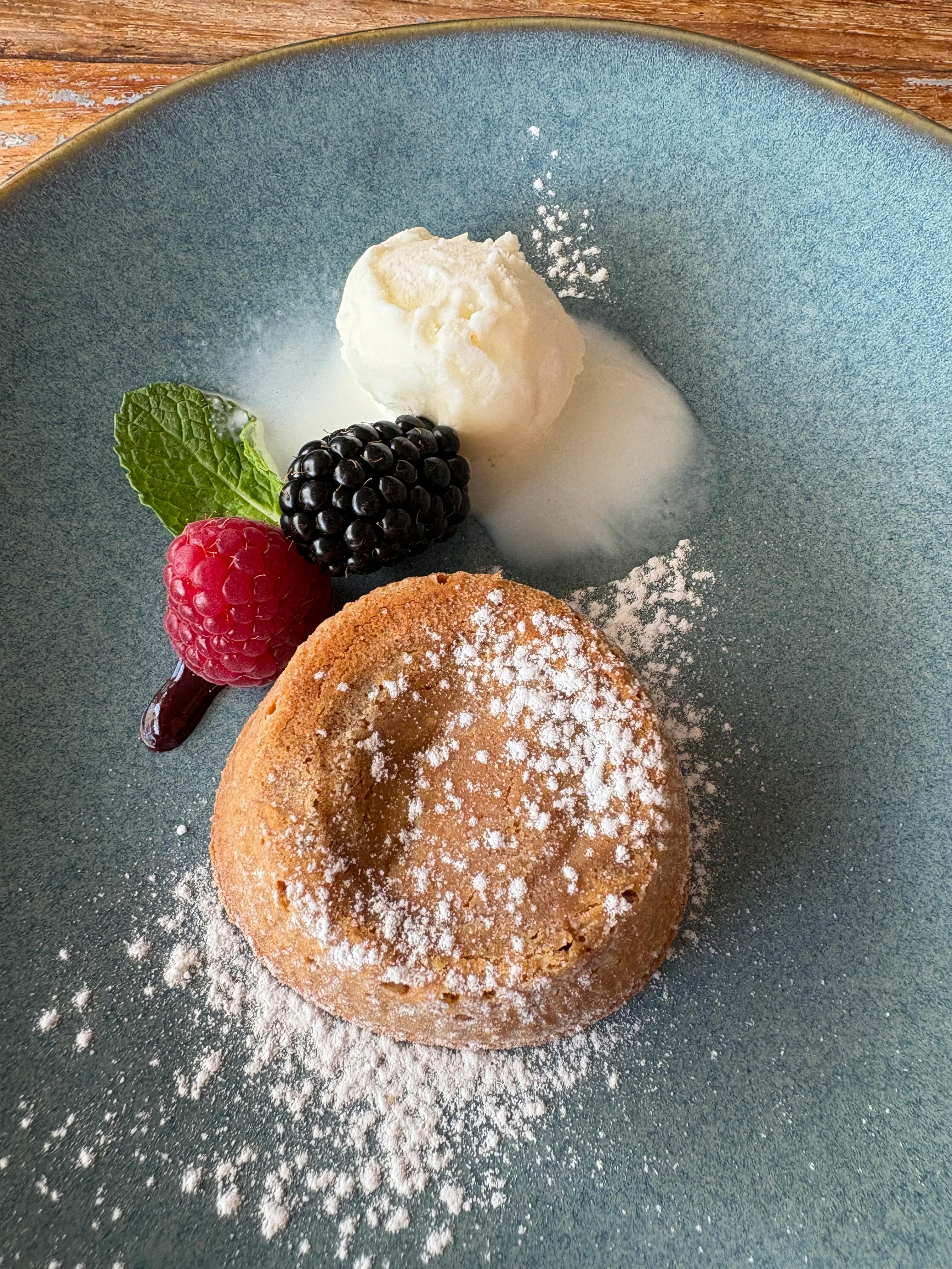 Zadarmo Lahodný dezert s lesným ovocím a zmrzlinou ozdobený mätou, podávaný na modrom tanieri. Fotka z fotobanky