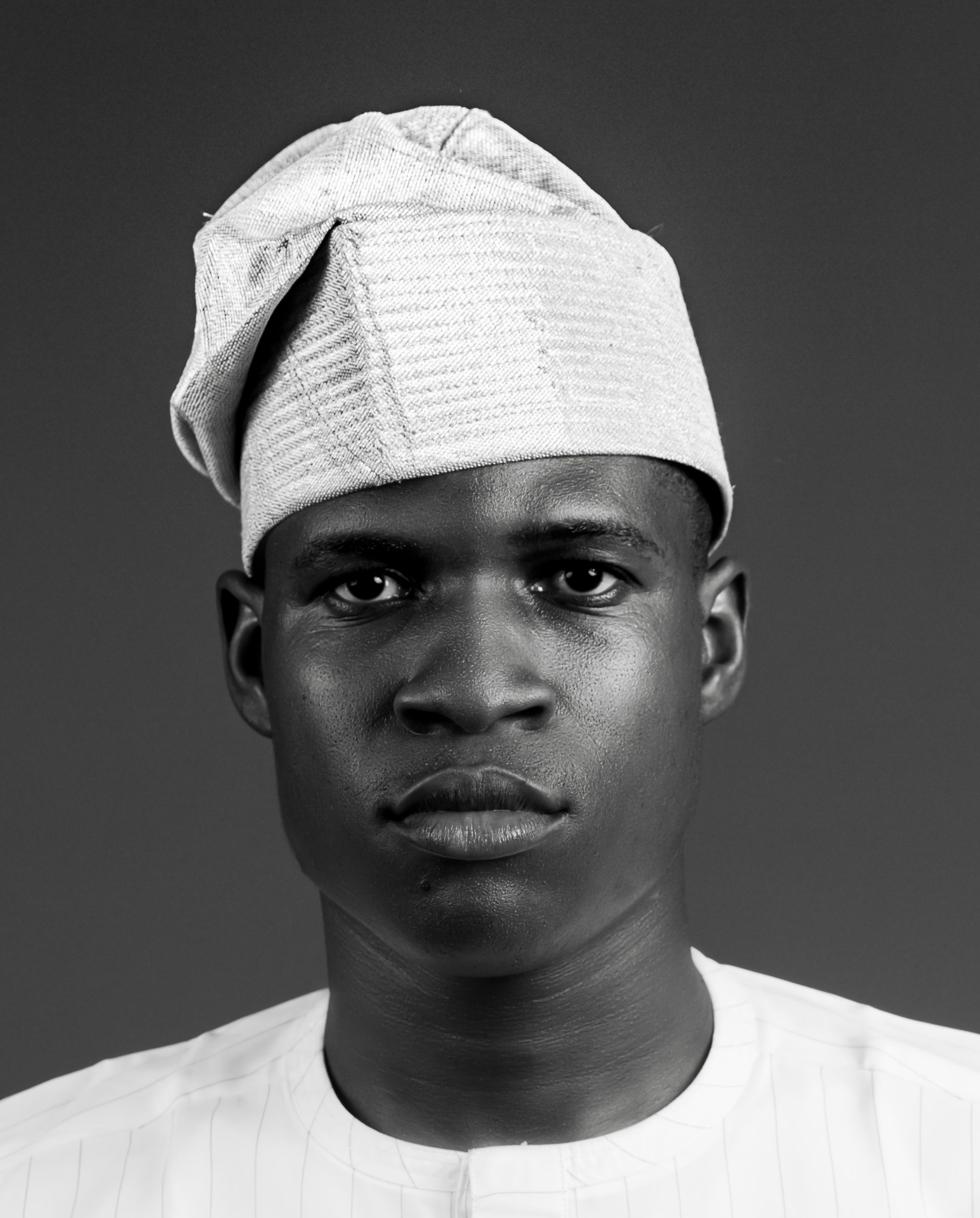 Black and white portrait of a man wearing traditional attire and headwear.