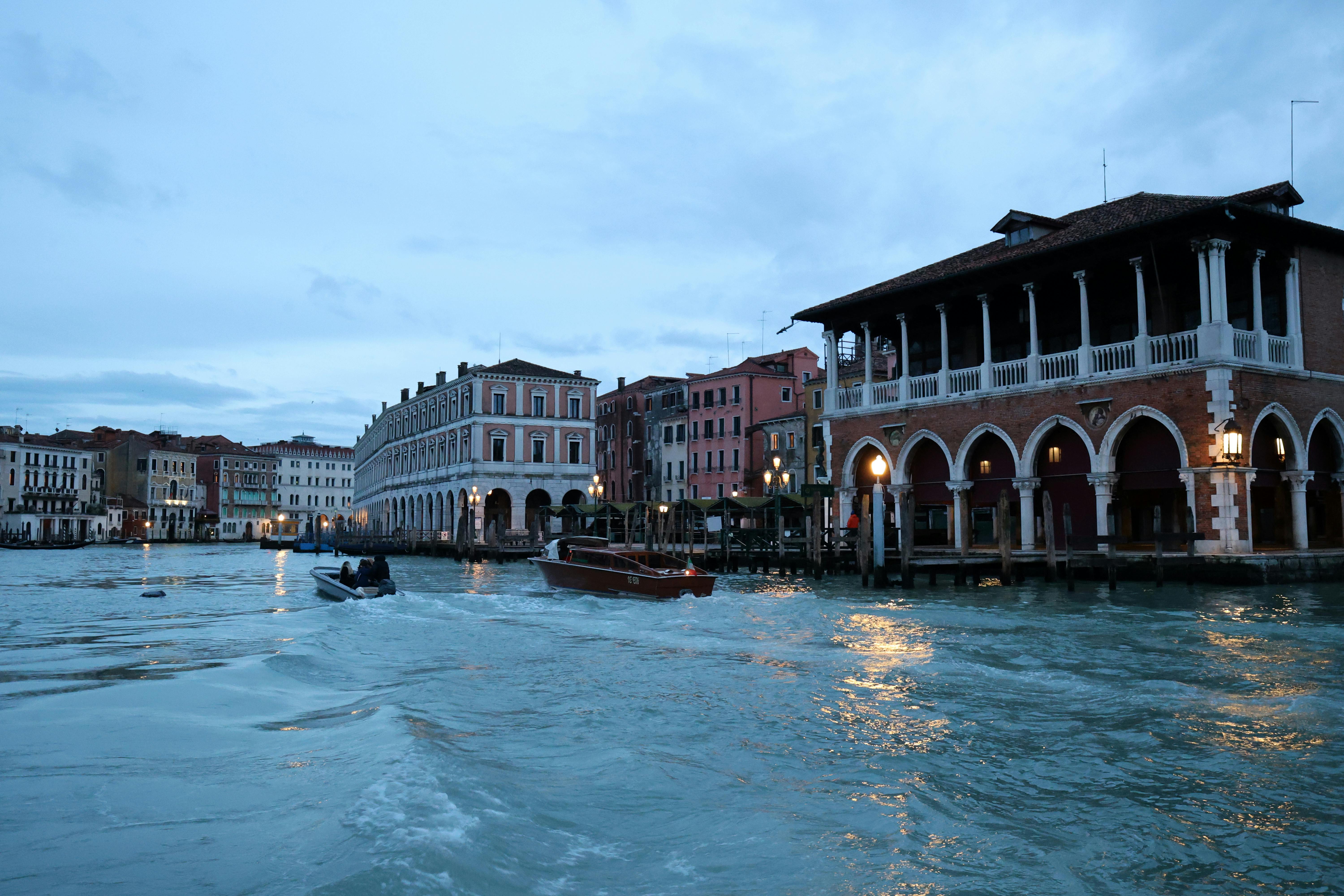 免費 捕捉威尼斯標誌性運河在藍調時刻的景象，展現了歷史悠久的建築和繁忙的水上交通。 圖庫相片