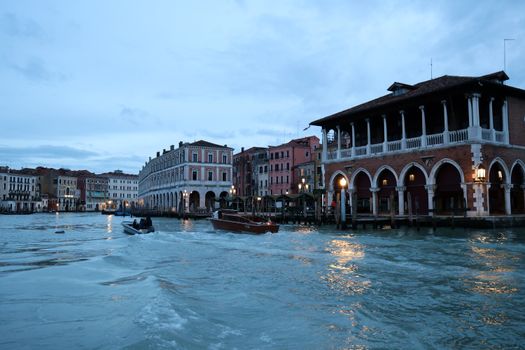 Capture of Venice's iconic canals at blue hour showcasing historic architecture and bustling watercraft.