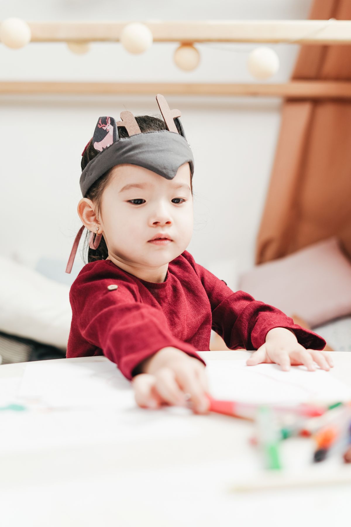A young child wearing a handmade crown while drawing her turkey headband feathers