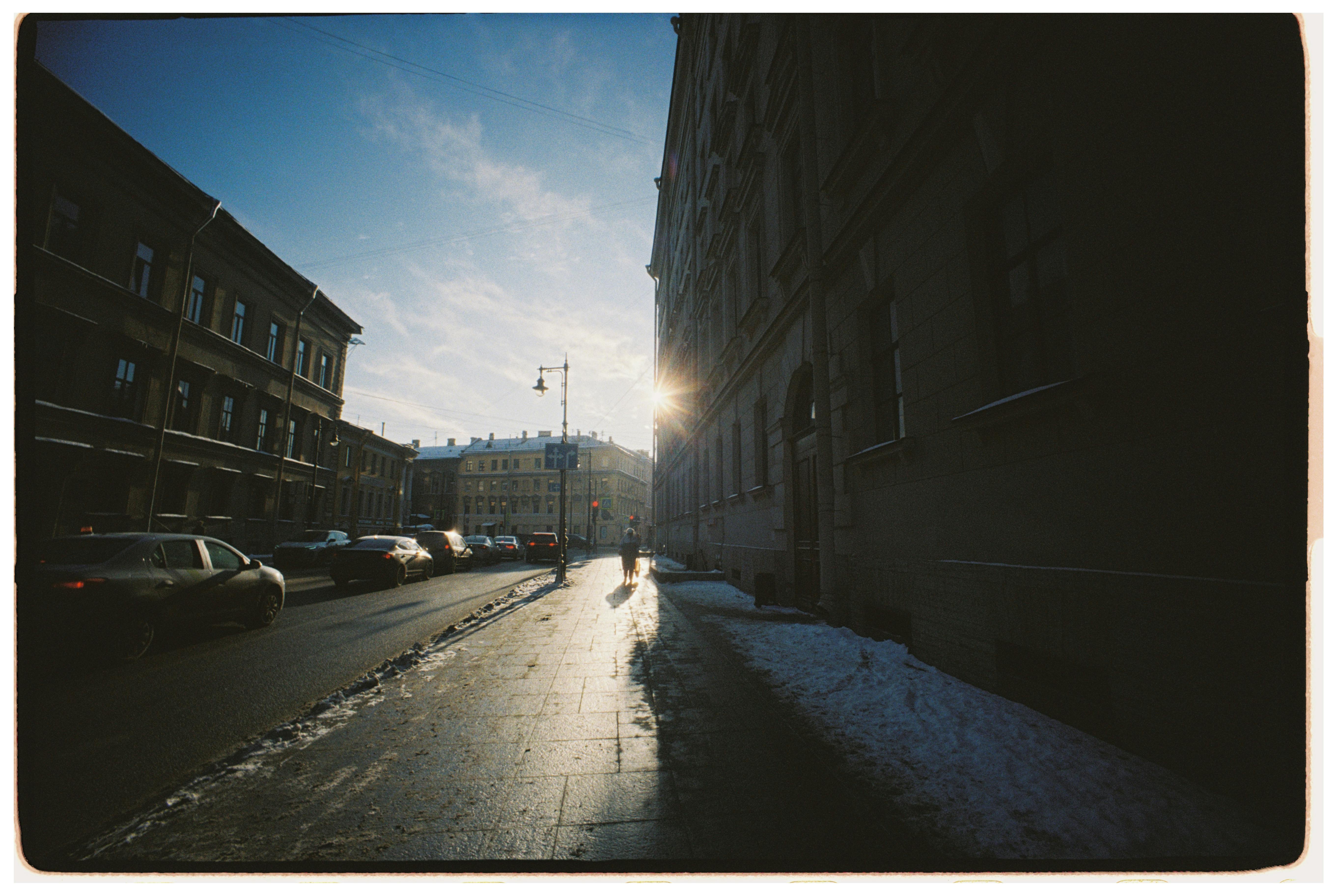 免費 冬日夕陽下的街景，汽車和行人投下長長的影子。 圖庫相片