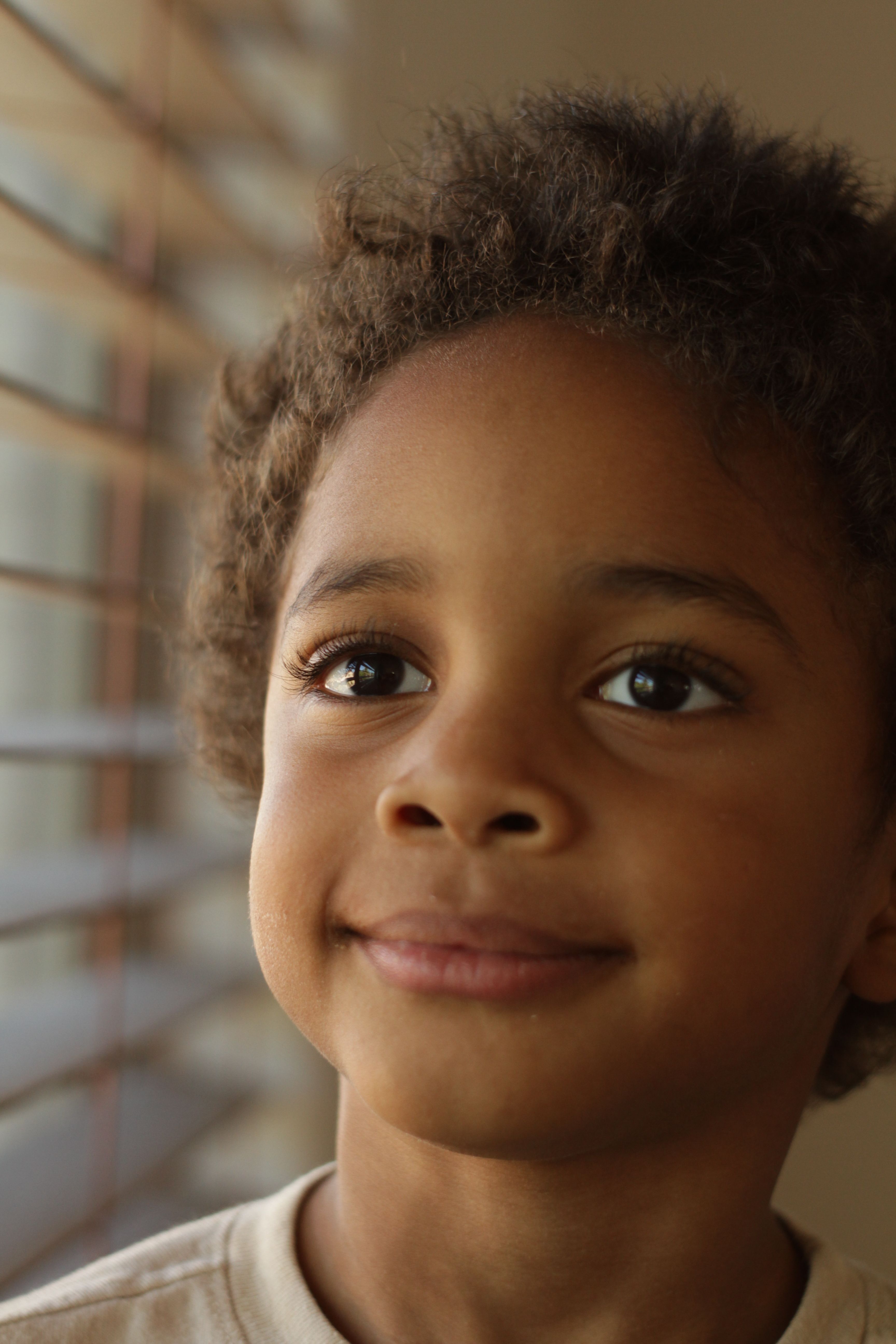 Joyful Child Looking Out the Window Indoors · Free Stock Photo