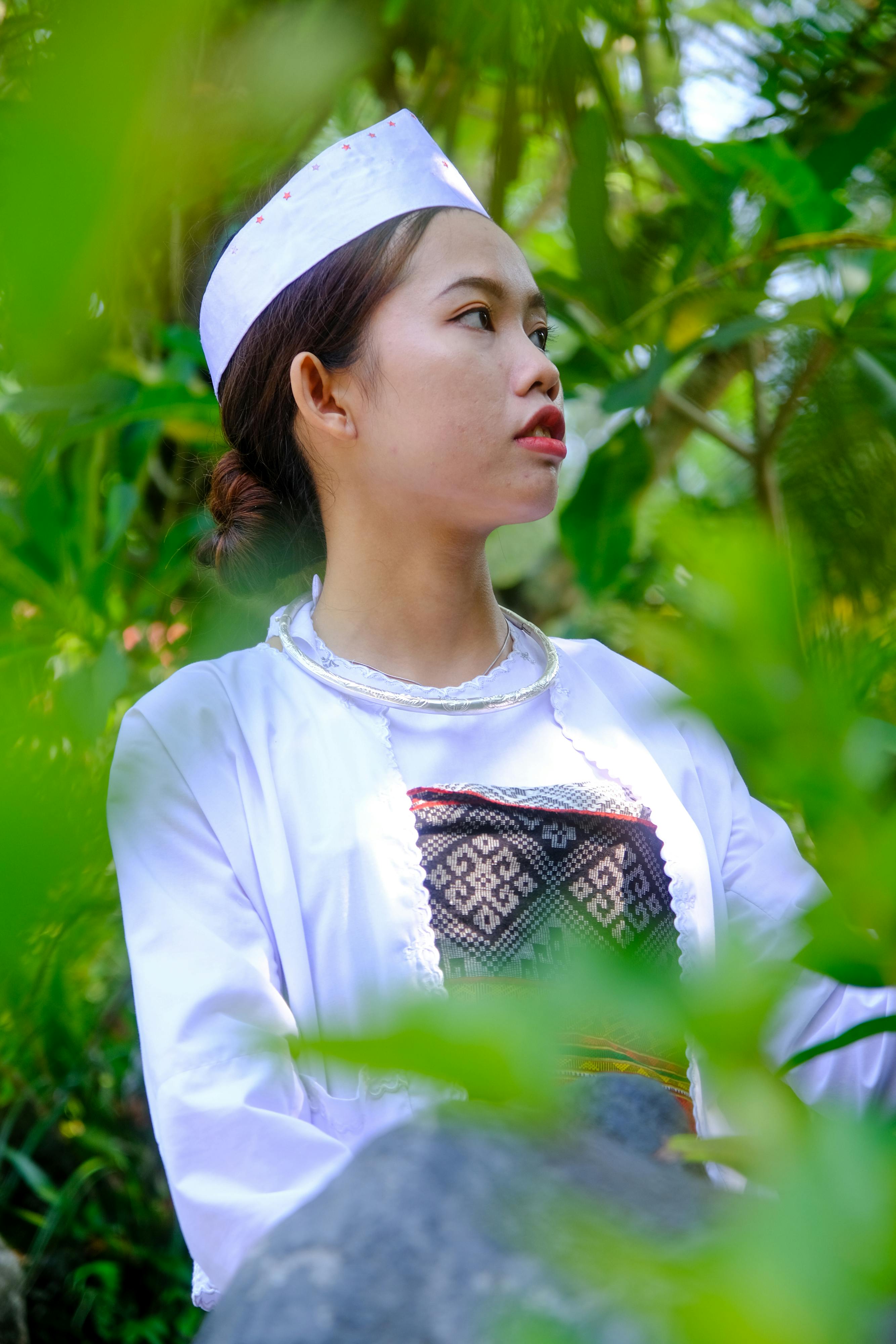 ฟรี หญิงสาวในชุดพื้นเมืองเวียดนามท่ามกลางพืชพรรณเขียวชอุ่มในเมืองเว้ ประเทศเวียดนาม คลังภาพถ่าย