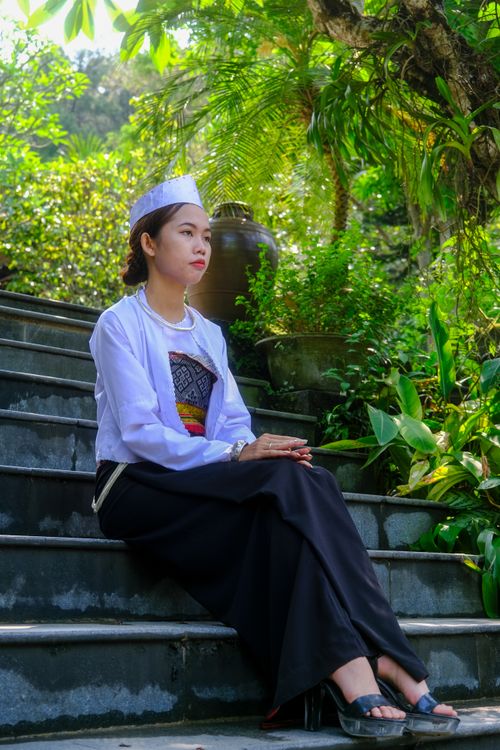 Free Portrait of a woman in traditional Vietnamese attire on garden steps in Hue, Vietnam. Stock Photo