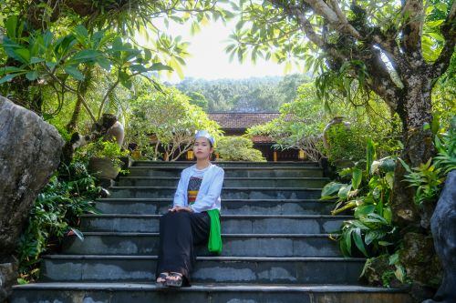 Free A woman in traditional clothing sitting on garden steps in Hue, Vietnam. Stock Photo