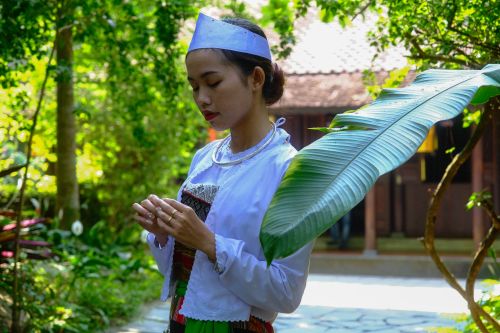 Free A woman in traditional attire stands serenely in a lush garden in Hue, Vietnam. Stock Photo