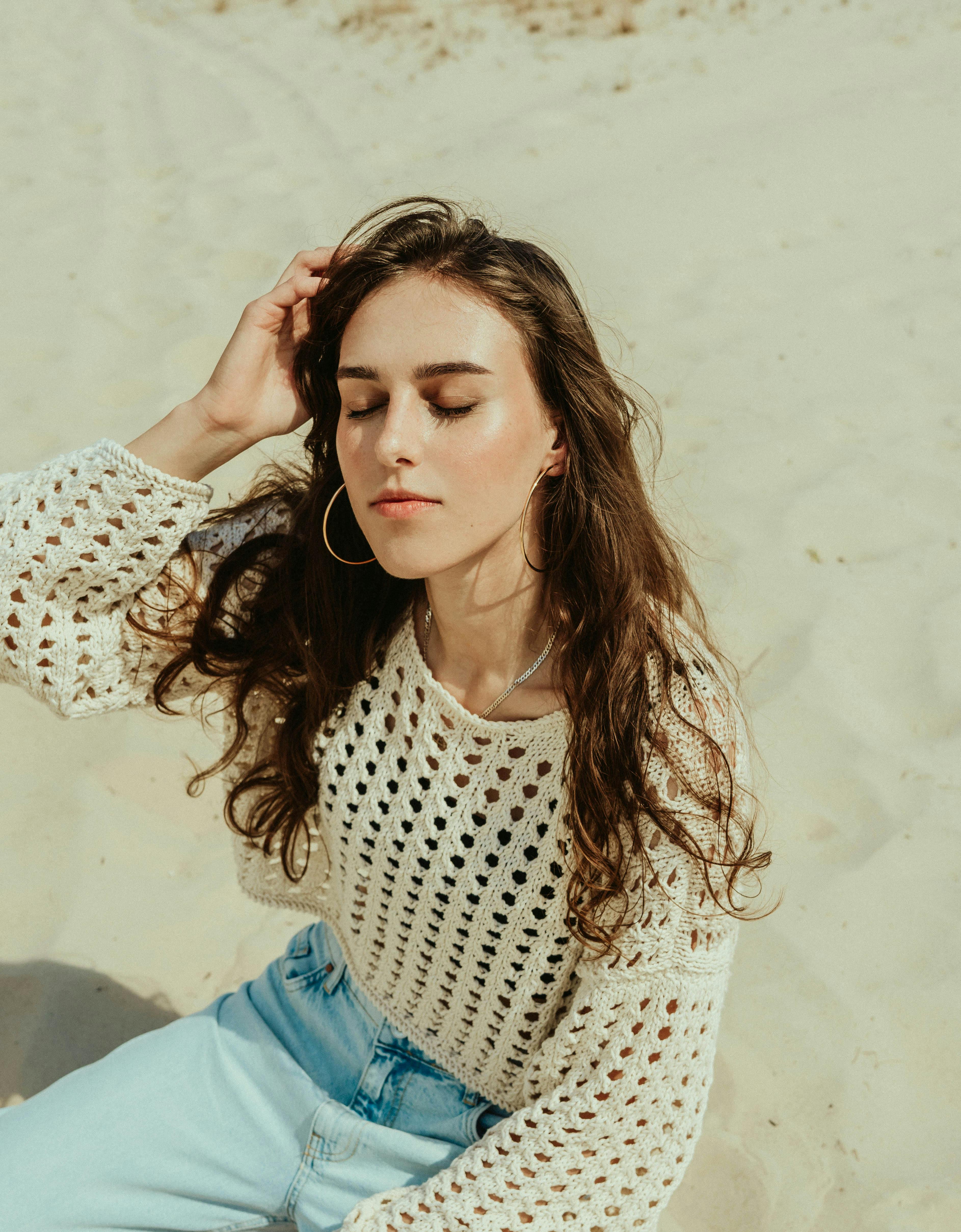 무료 한 여성이 햇살 좋은 날 모래사장에서 눈을 감고 편안하게 휴식을 취하고 있다. 스톡 사진