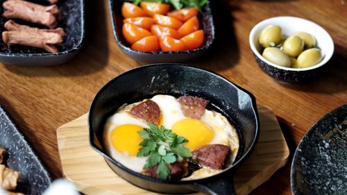 Free A savory breakfast featuring sunny-side eggs, sausage, cherry tomatoes, and olives. Stock Photo