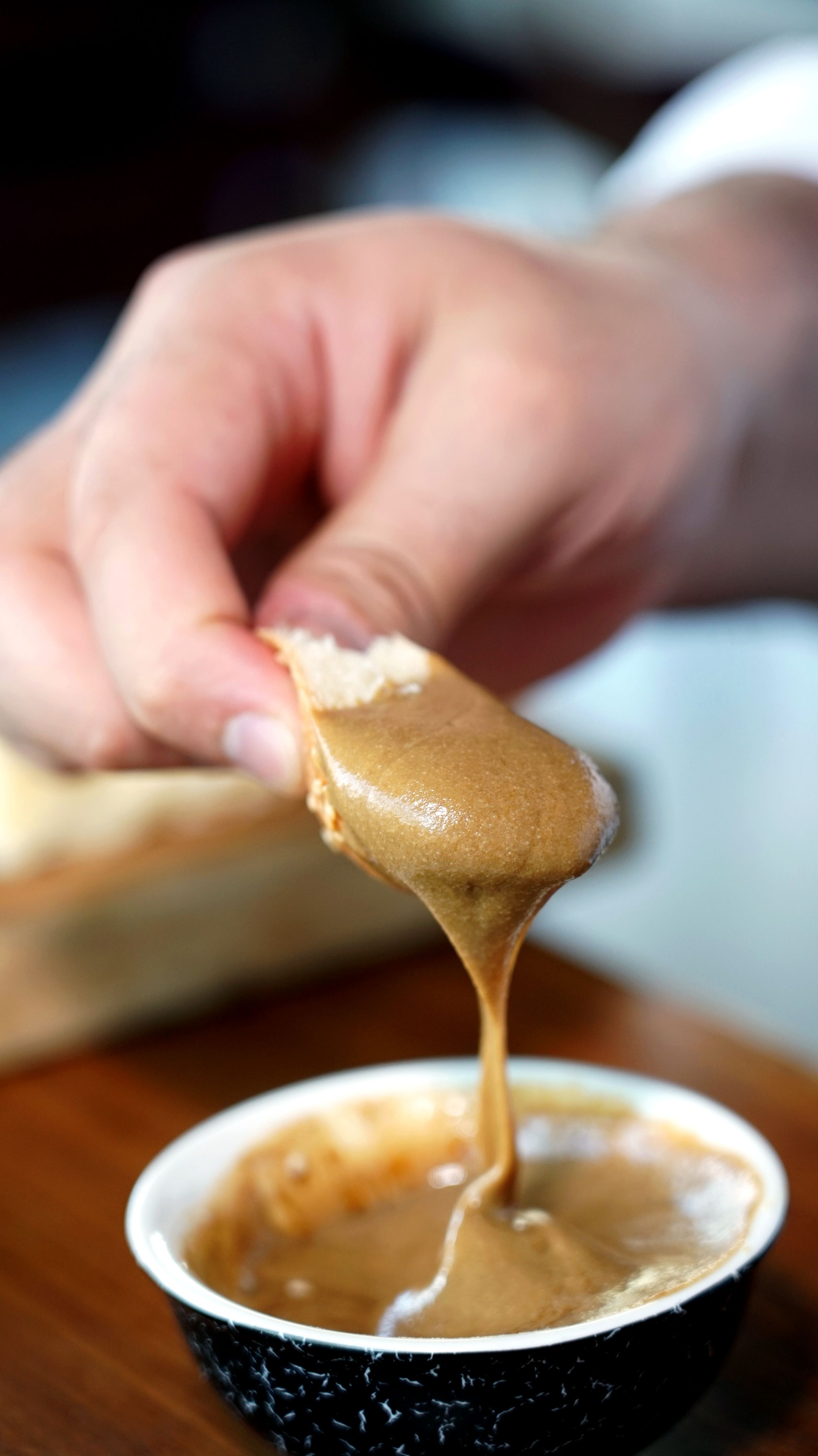 Close-up of smooth peanut butter dip being scooped with bread slice, highlighting creamy texture.