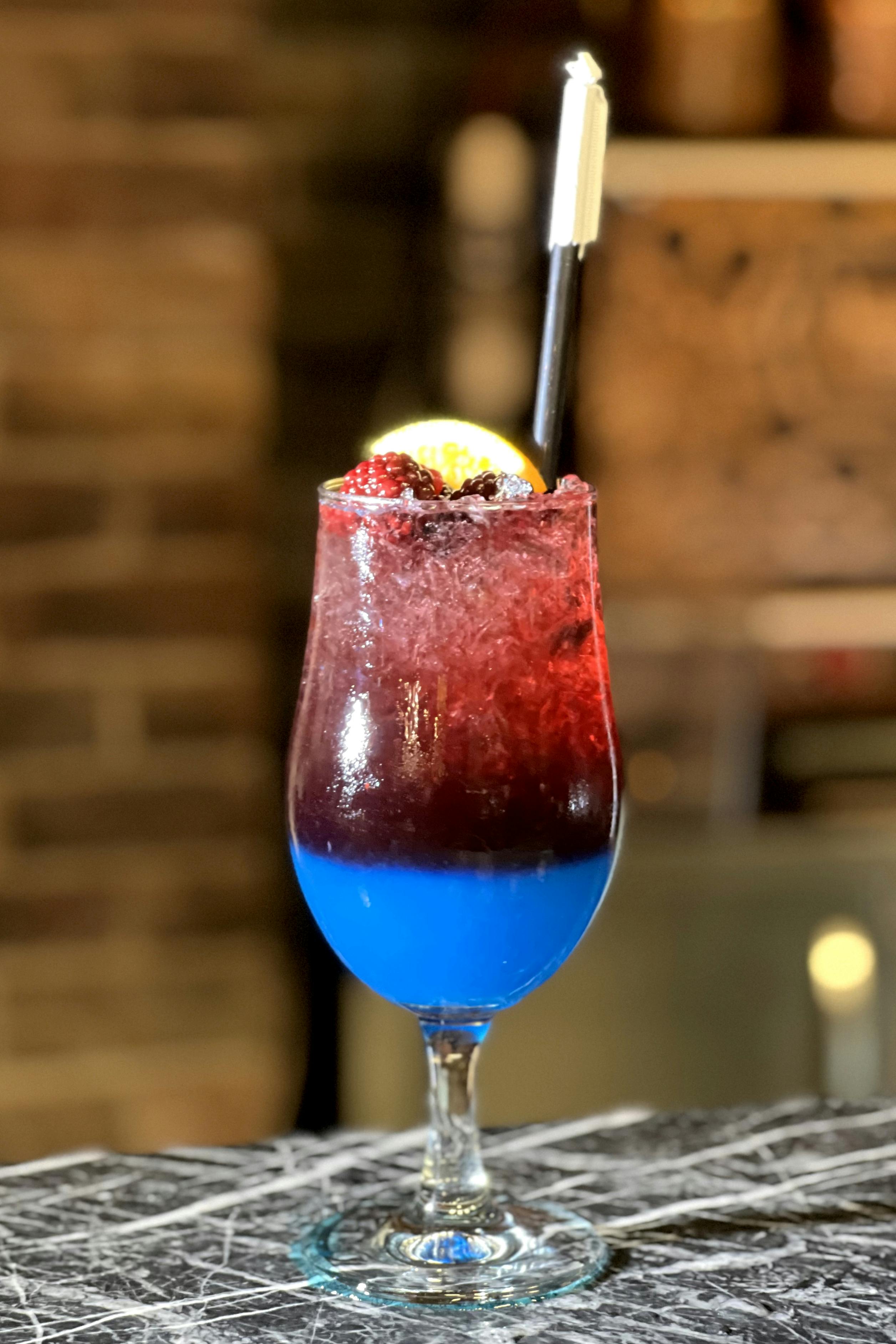 Zadarmo Živý vrstvený kokteil s bobuľami, limetkou a slamou na barovom pulte. Fotka z fotobanky