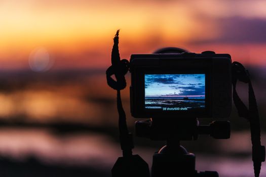 Camera captures a beautiful sunset over the sea, highlighting the art of photography.
