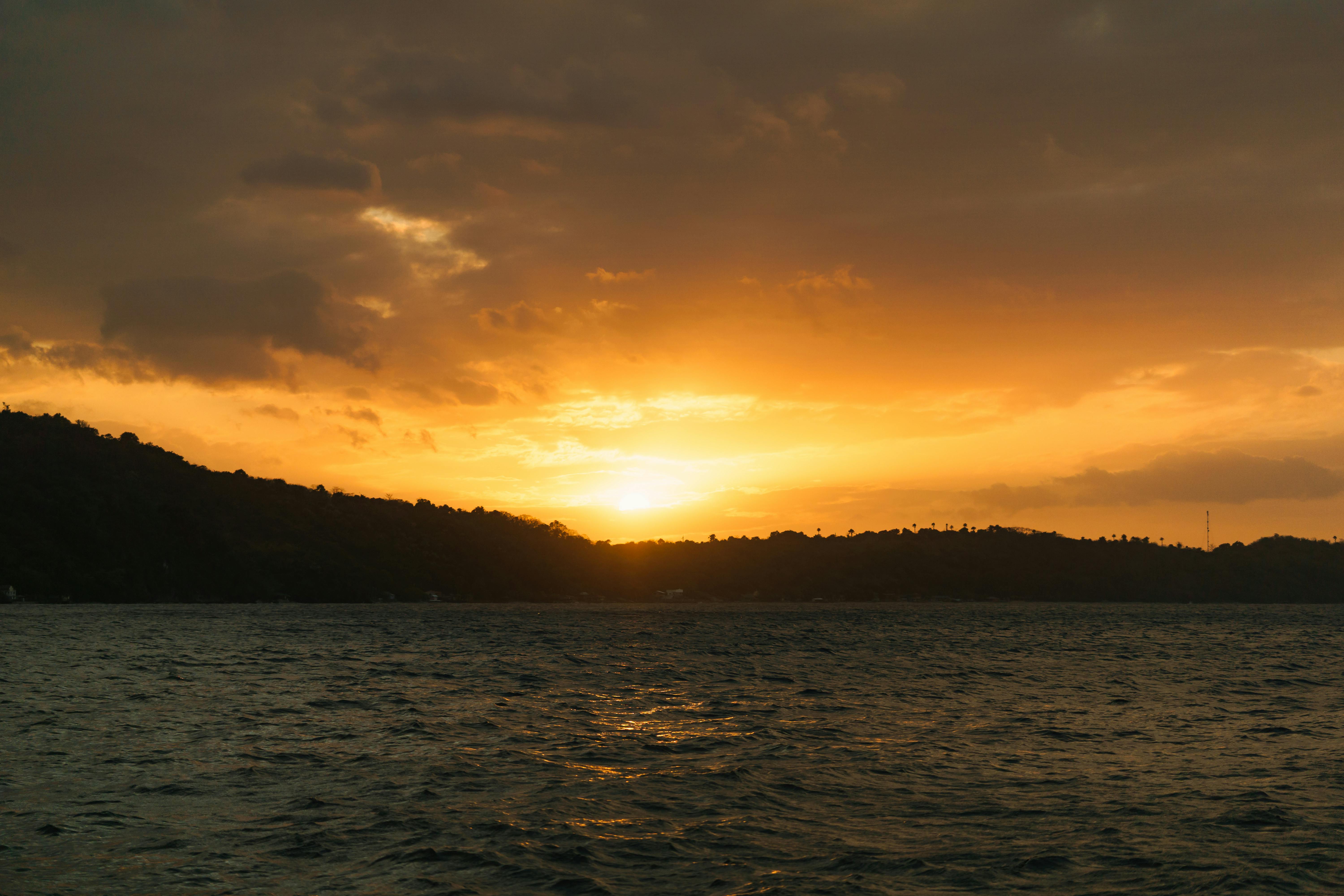 Безкоштовне Захопливий захід сонця над океаном із золотим небом та спокійною водою, ідеально підходить для релаксації. стокове фото