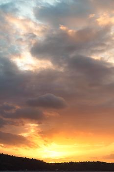 Stunning view of a colorful sunset sky with clouds over a serene hillside landscape.
