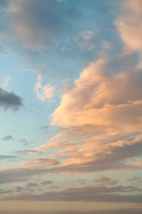 Free Capture the tranquil beauty of a sunset sky filled with soft pastel clouds and warm hues. Stock Photo