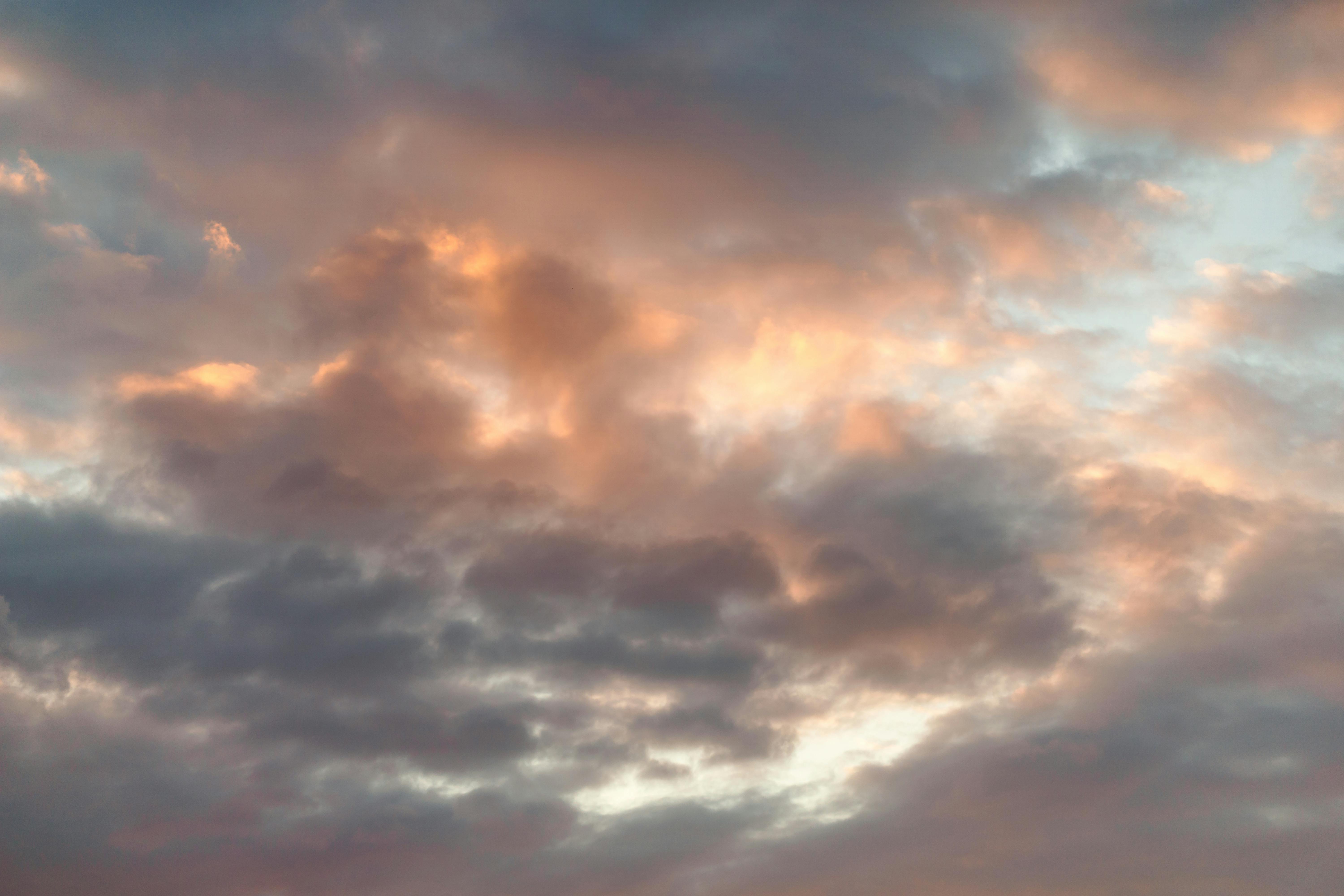 ingyenes Egy nyugodt égbolt, melyet rózsaszín és narancssárga árnyalatú felhők töltenek meg naplemente közben, nyugalmat sugározva. Stockfotó