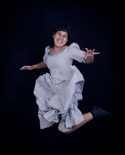 Free Happy woman in a vintage dress leaping joyfully against a dark background. Stock Photo